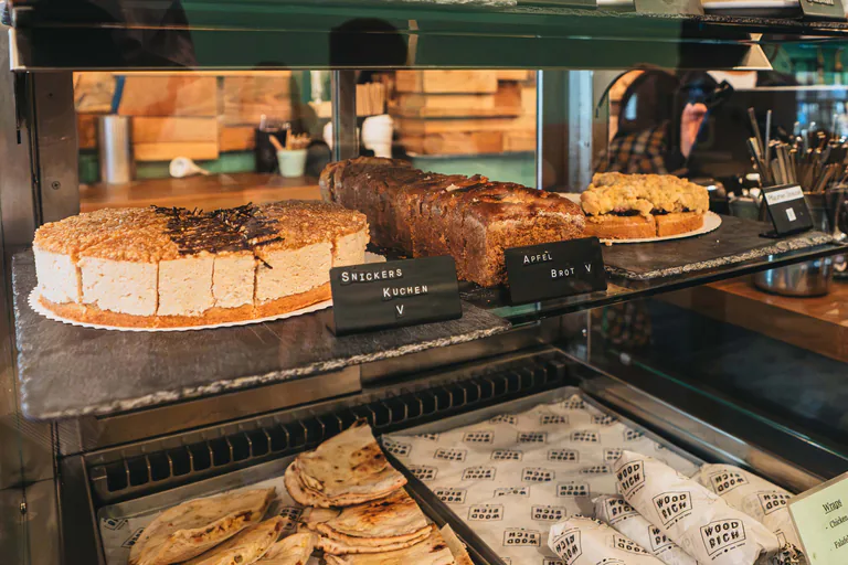 Kuchen und Brote in der Vitrine, darunter Panini und in Woodrich-Papier gewickelte Wraps